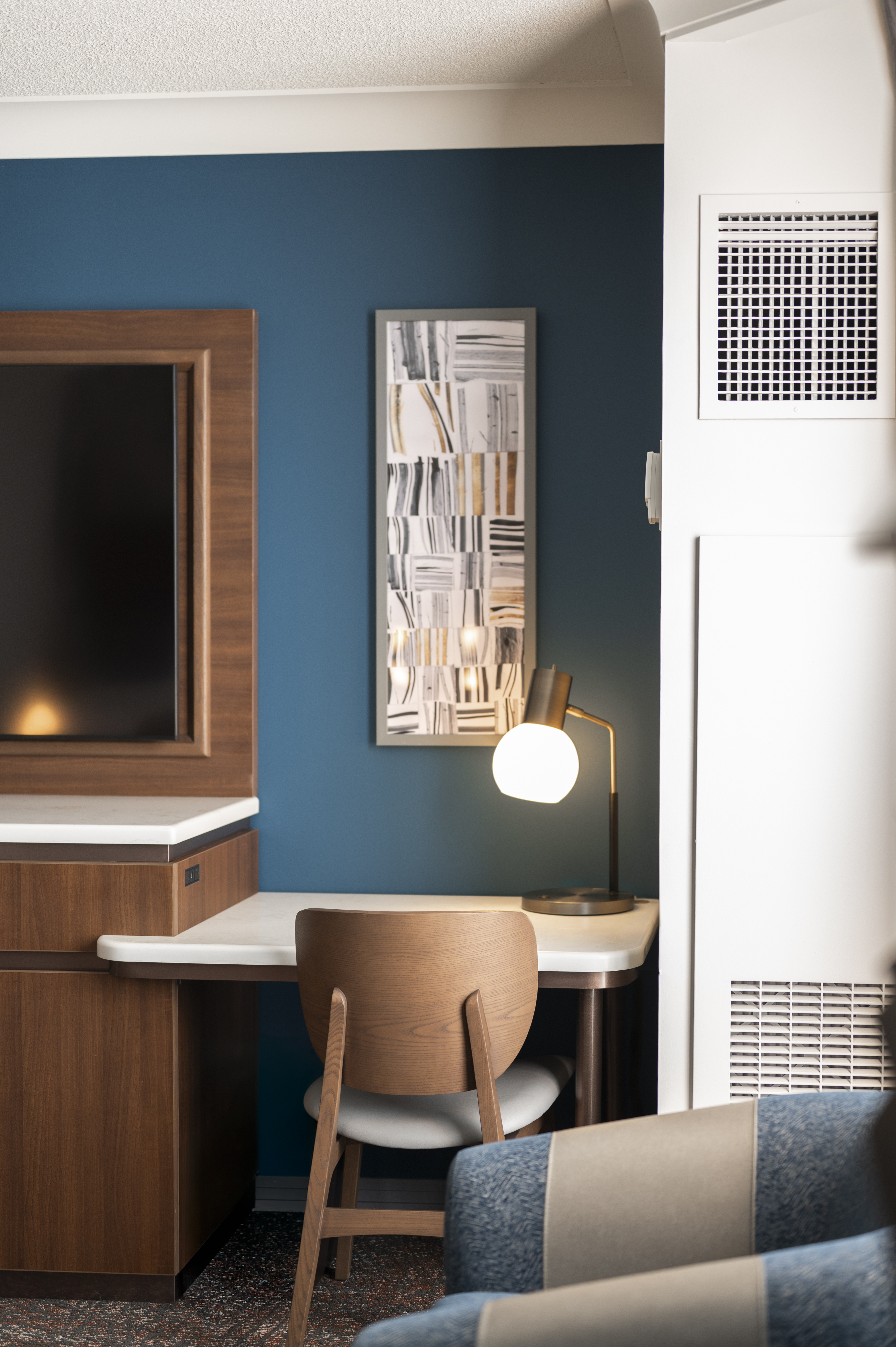 Hotel room desk and chair with a teal accent wall and modern artwork