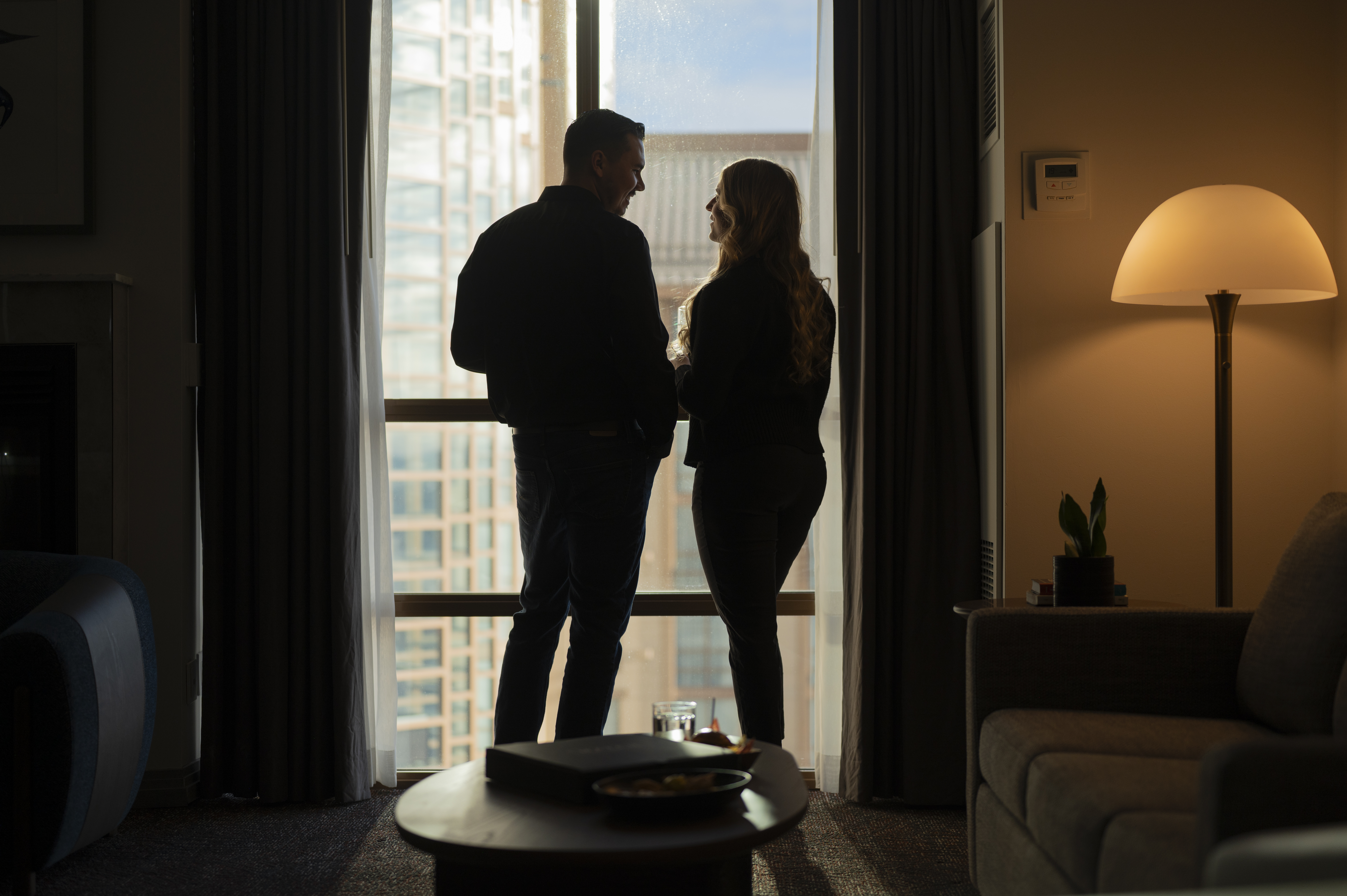 Man and woman standing by a large window overlooking a city