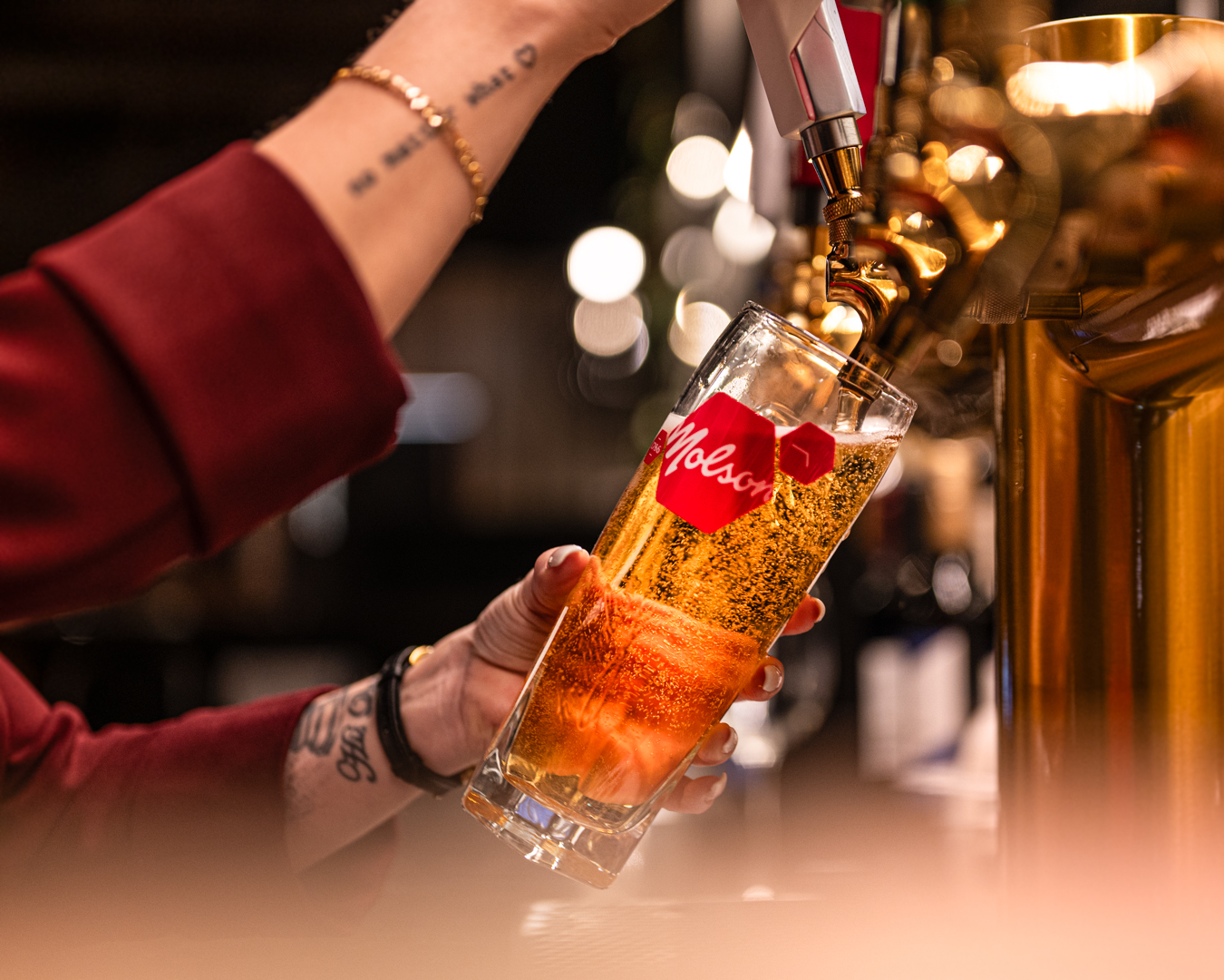 Bartender pouring a refreshing glass of Molson beer from a golden tap