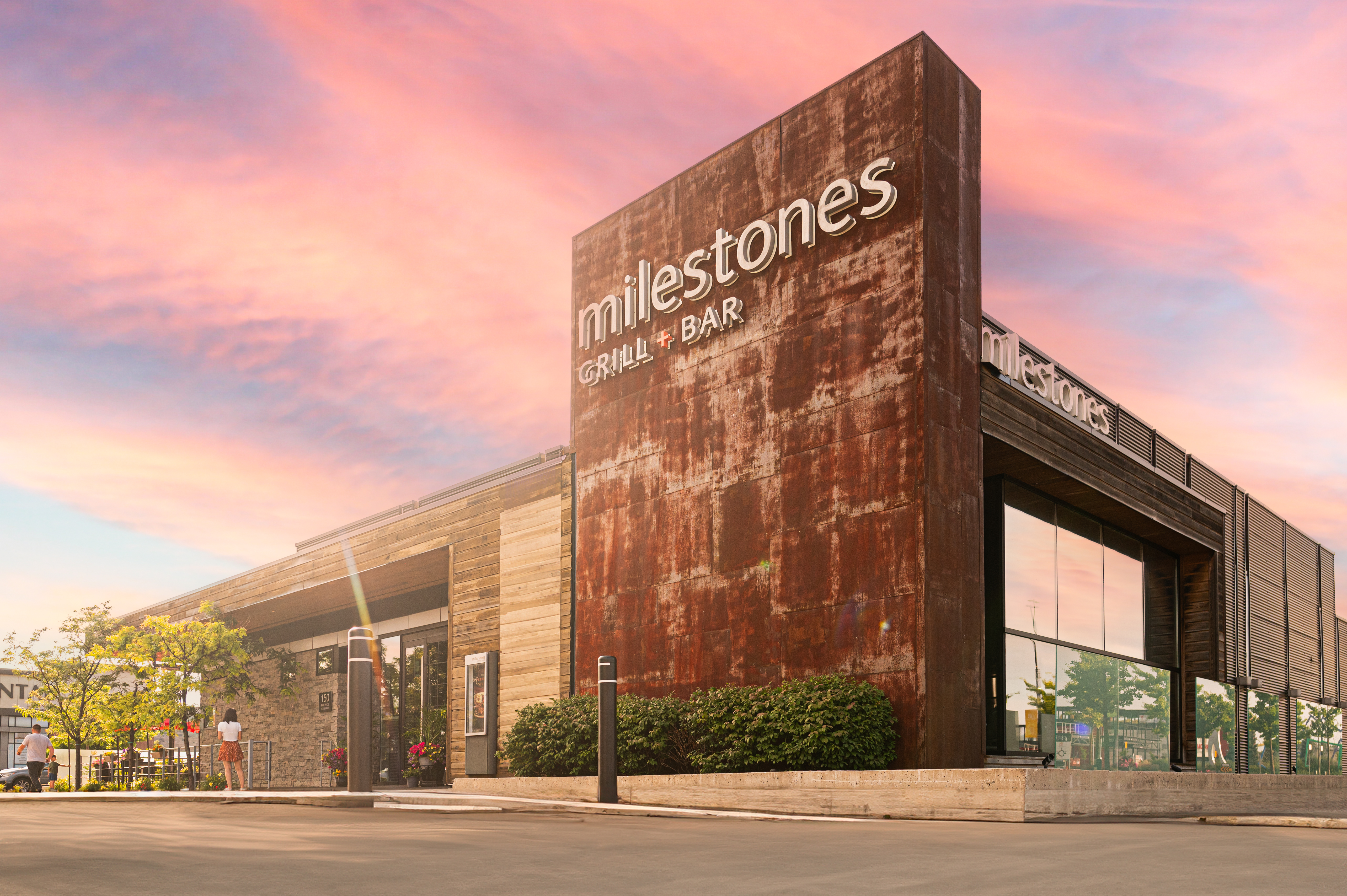 Milestones Grill + Bar restaurant exterior under a vivid pink and orange sunset sky
