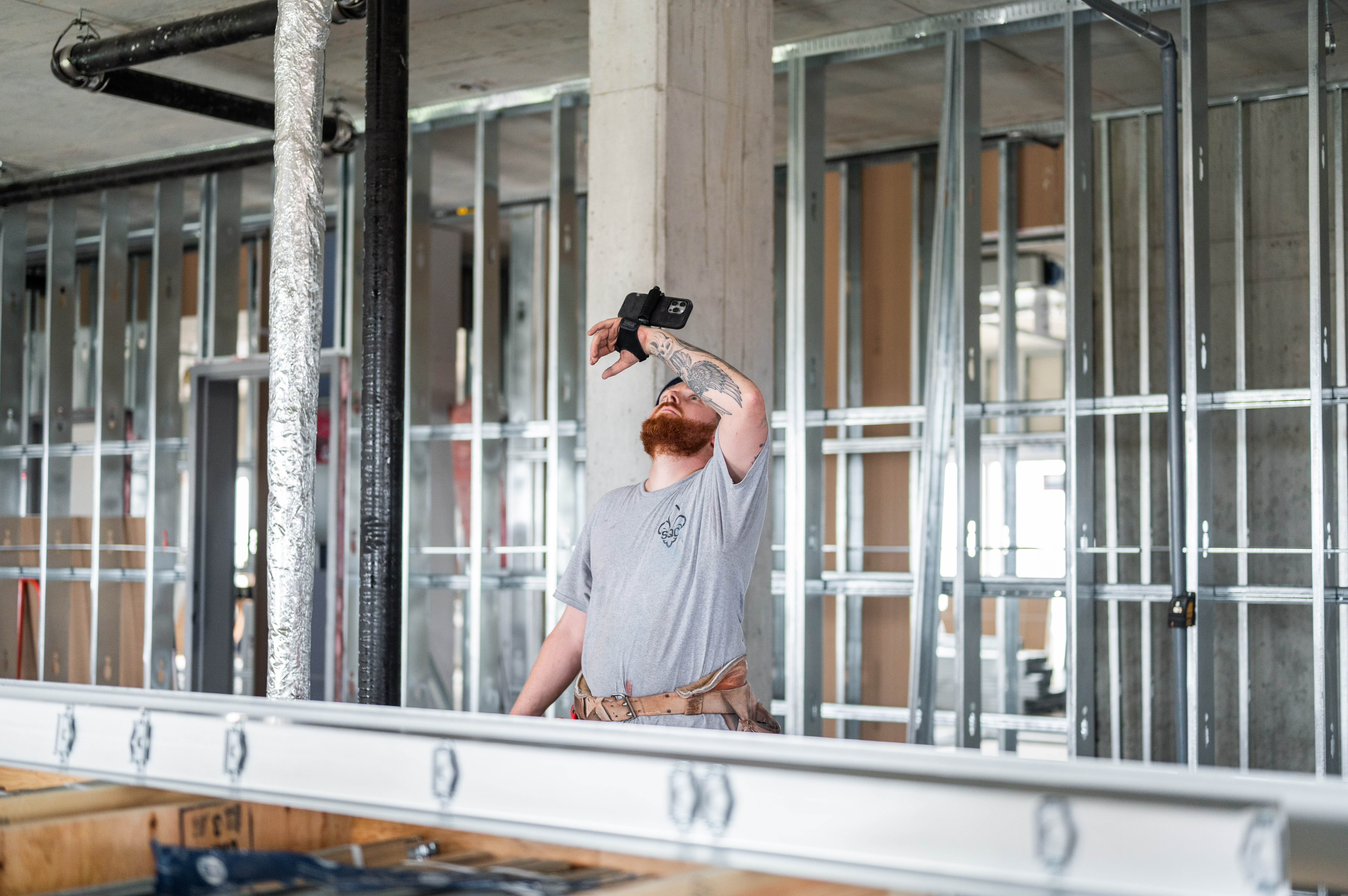 Construction worker with phone-mounted device inspecting unfinished building interior