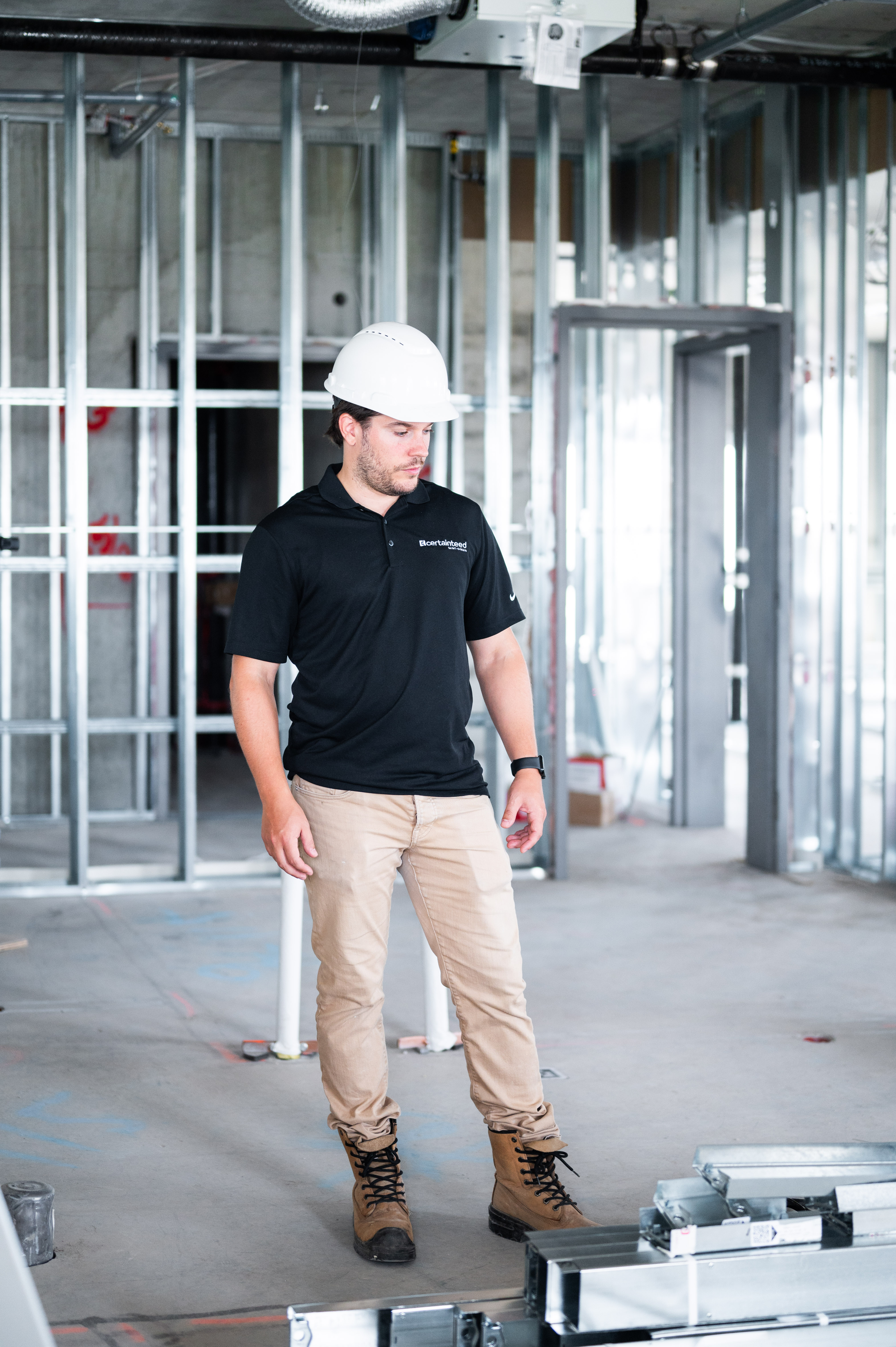 Construction worker in hard hat and polo shirt inspecting a building under construction