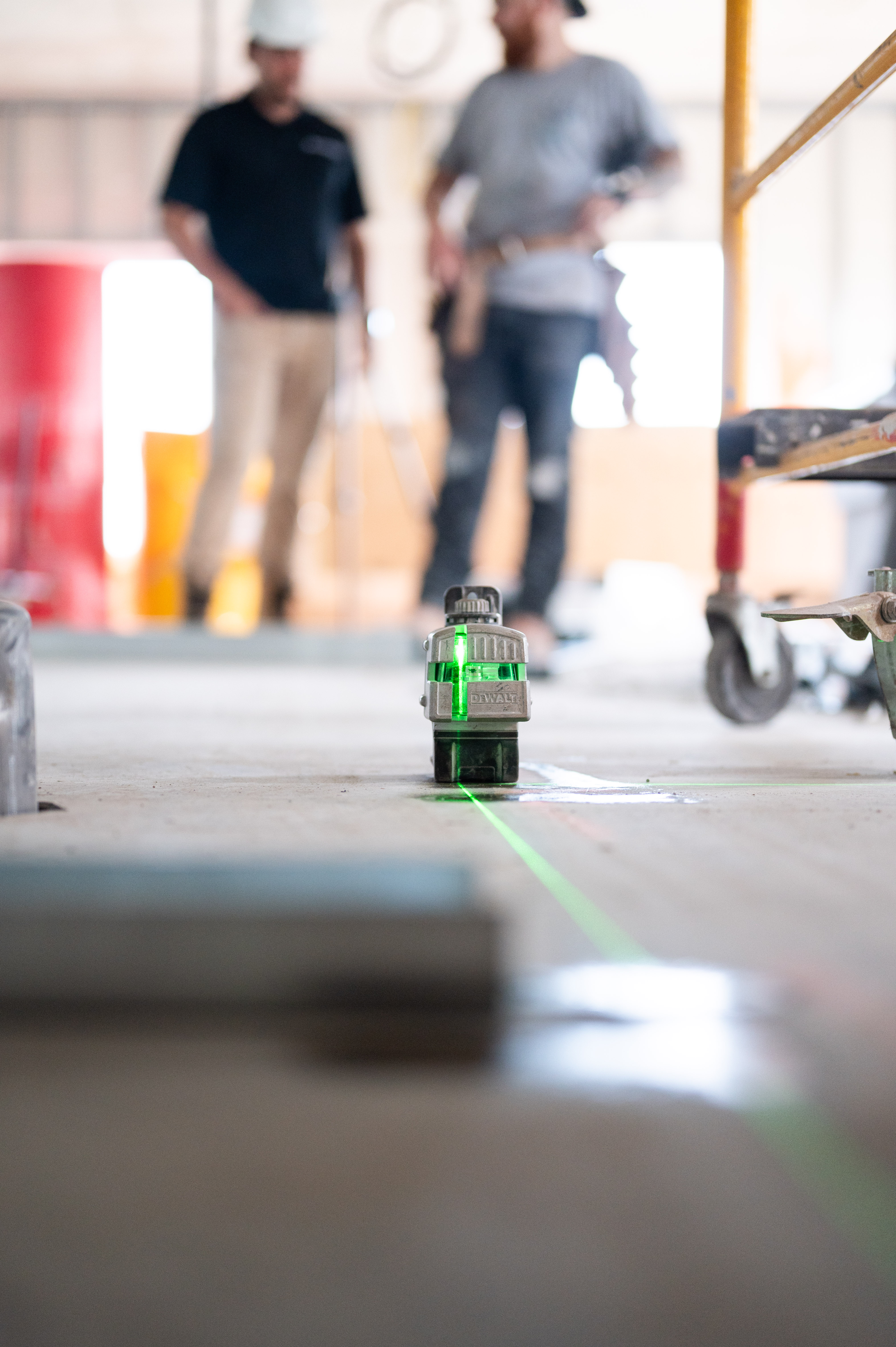 DeWalt laser level casting a green line across a concrete floor at a job site