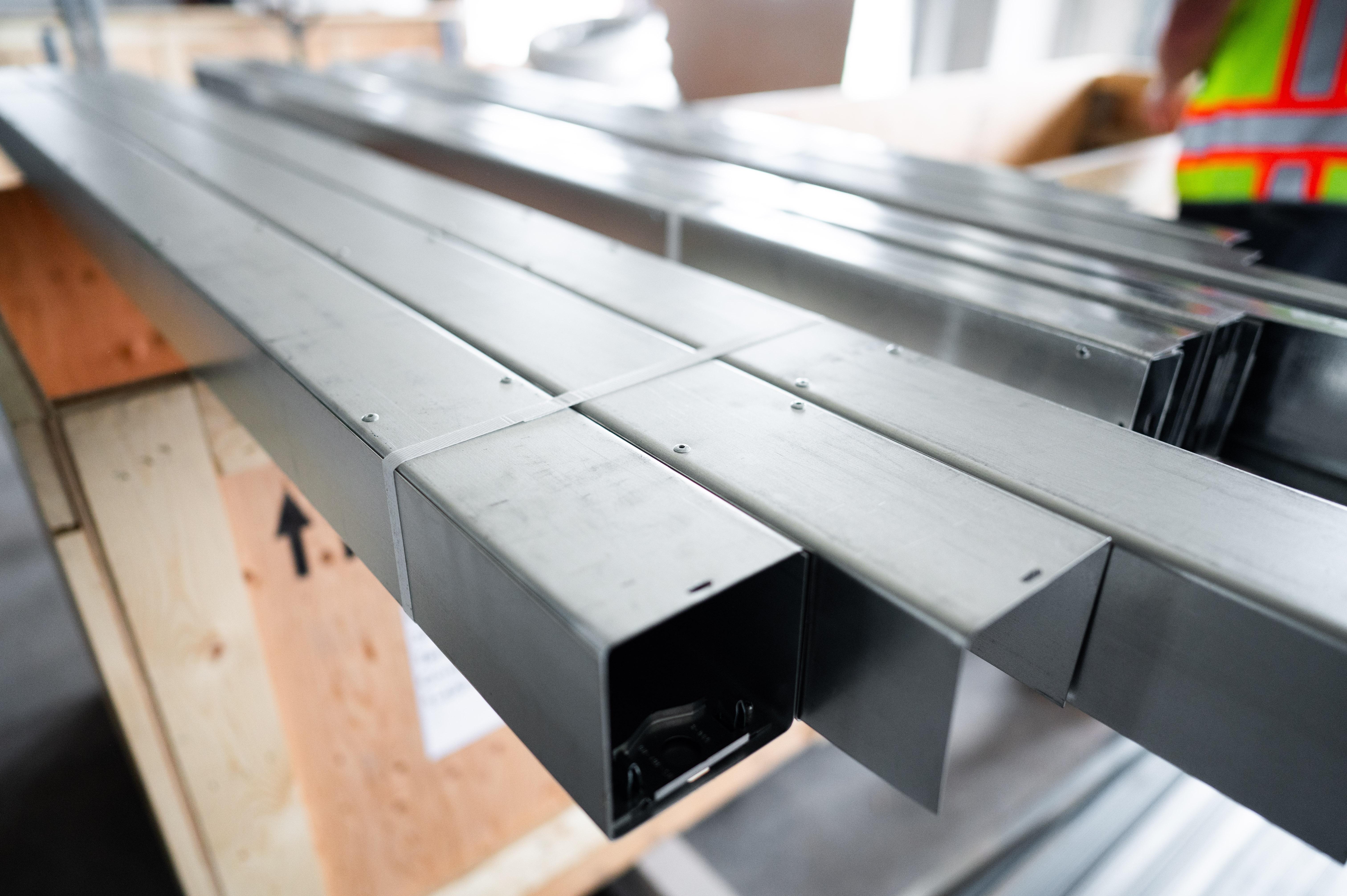 Bundled gray metal conduit channels on a wooden crate in a corporate warehouse setting