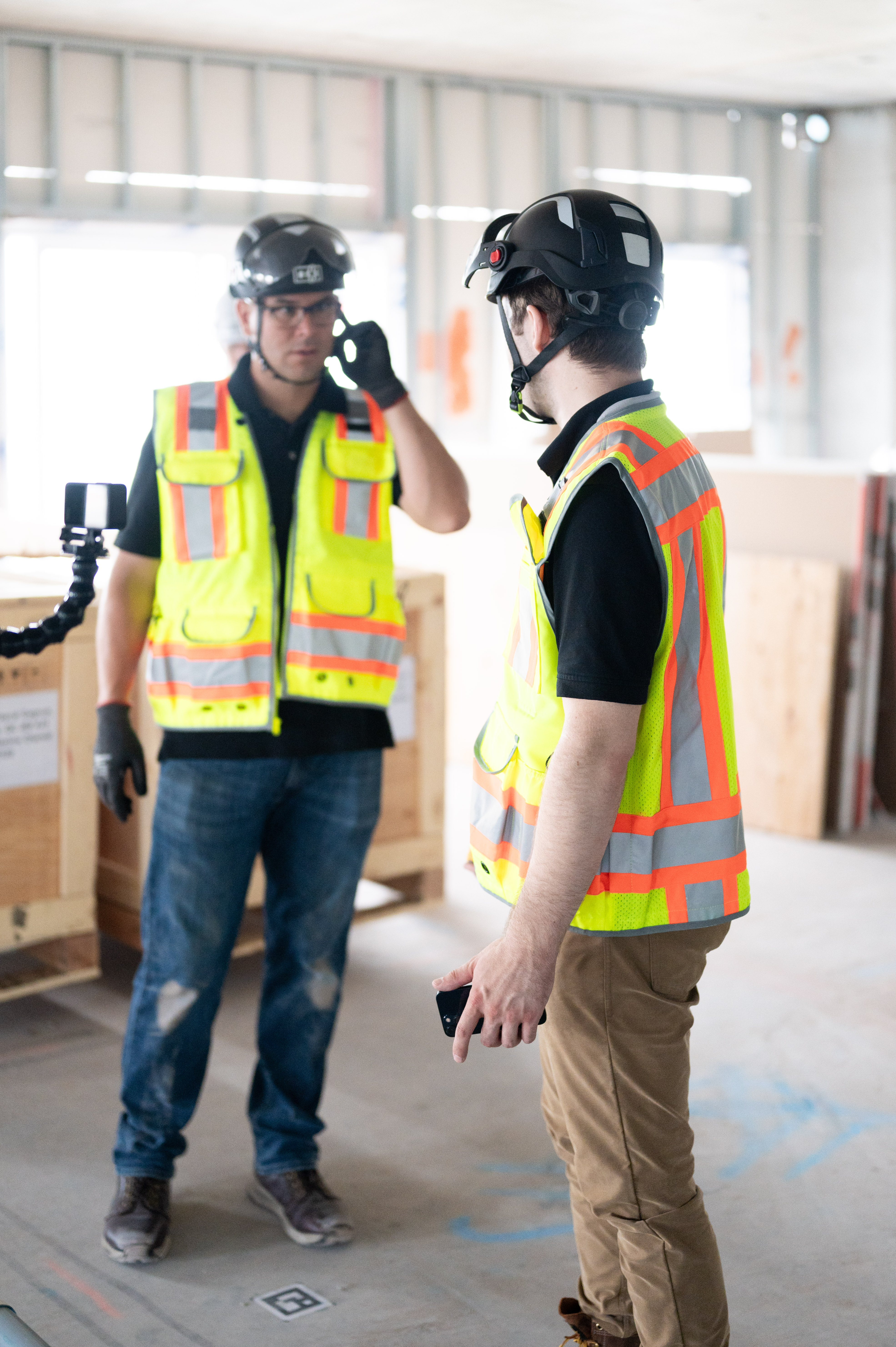 Two construction workers in safety gear discussing a project on-site
