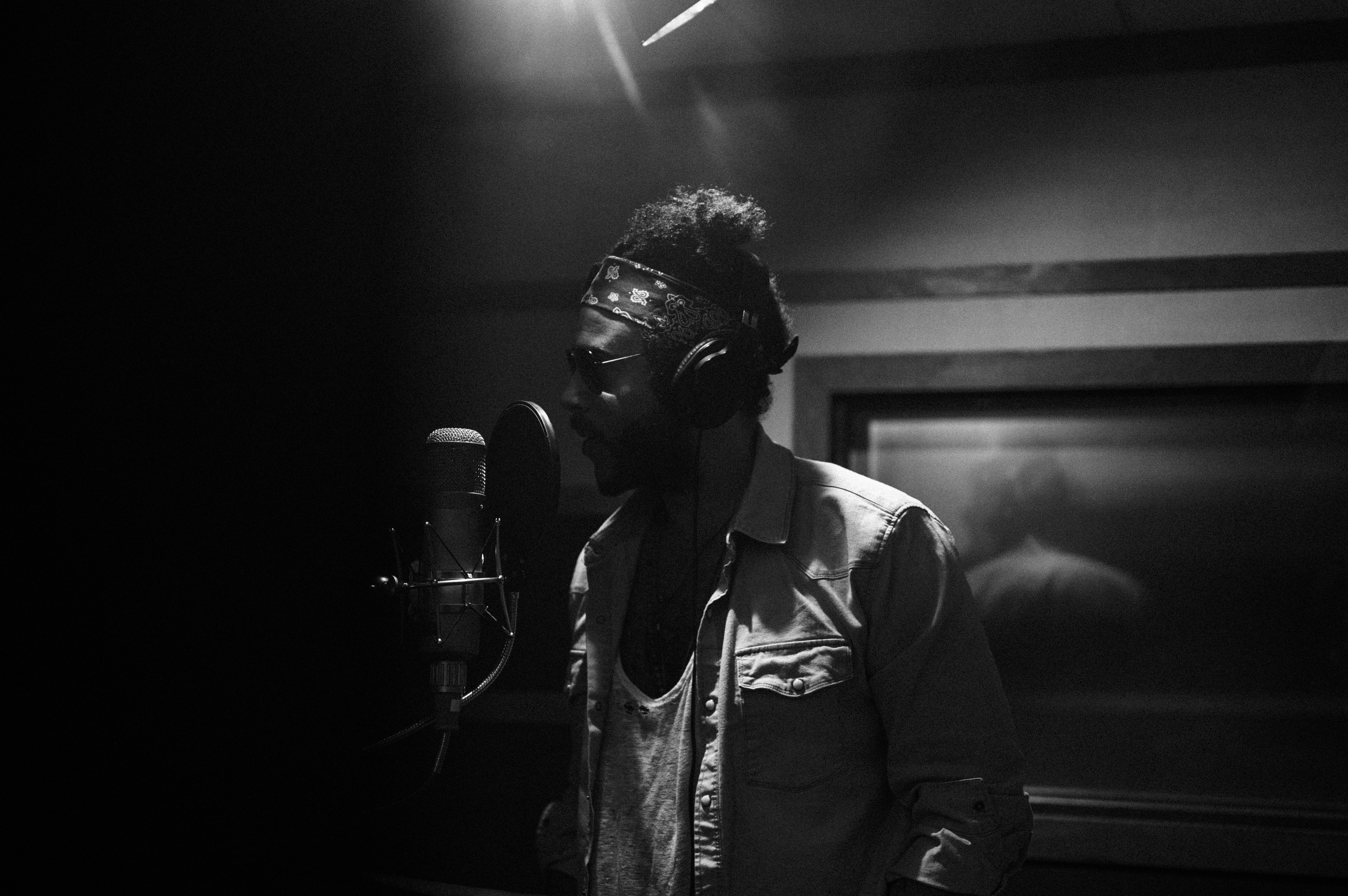 Sons of Legion band member recording vocals in a dark studio, black and white