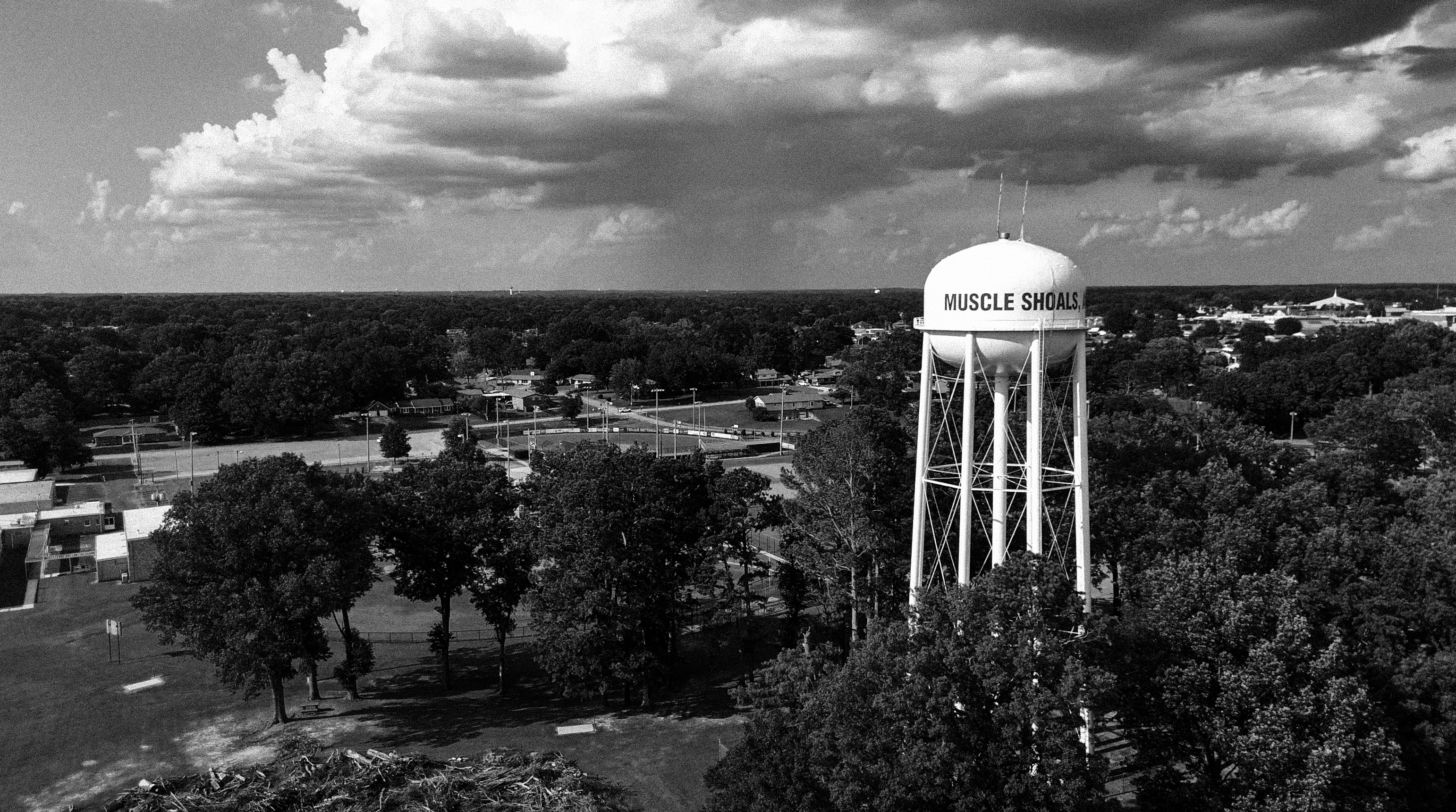 Black and white aerial view of the Muscle Shoals water tower against a cloudy sky