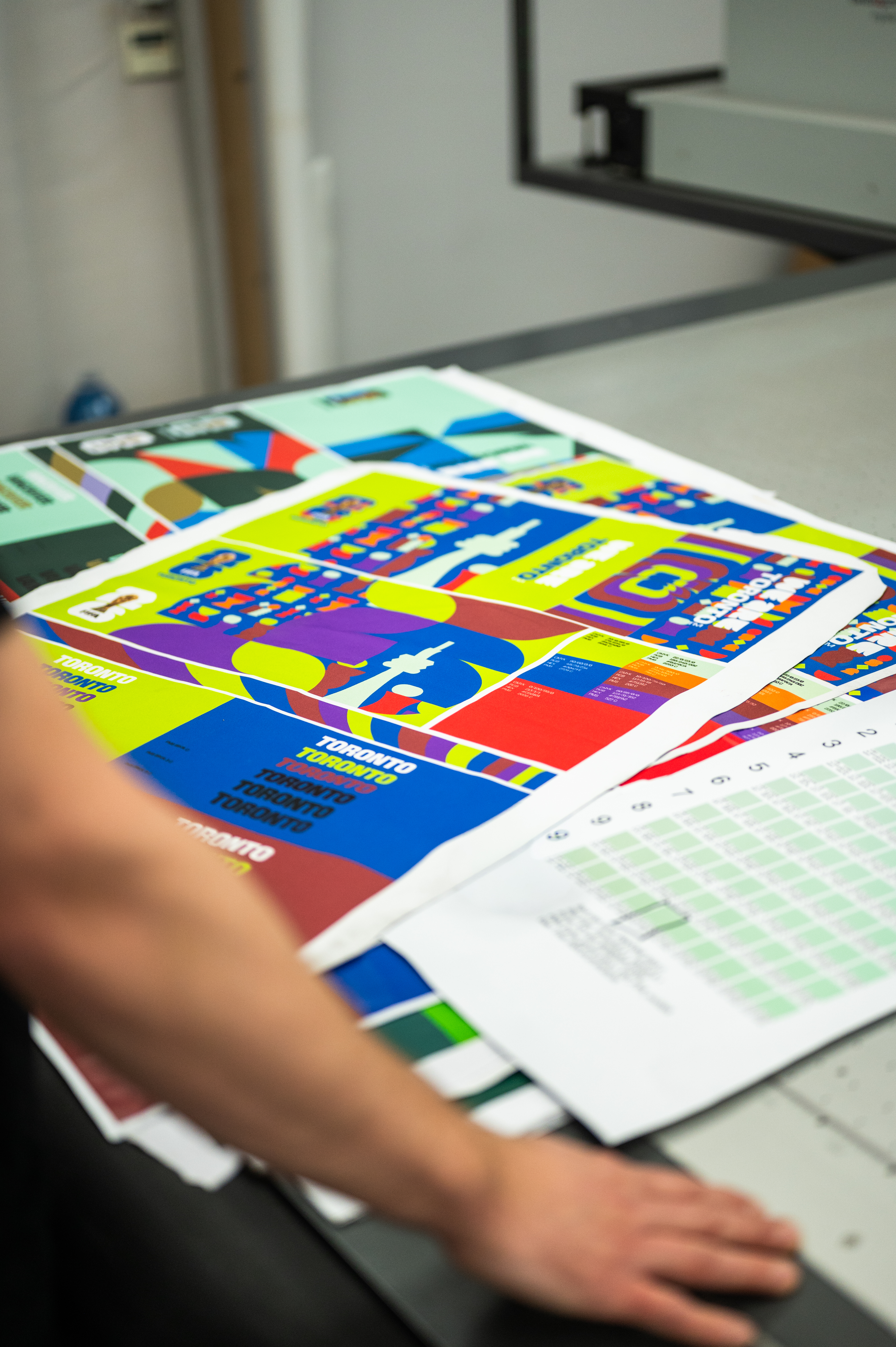 Multiple colorful printed proofs for the FIFA World Cup 2026 Toronto branding designs