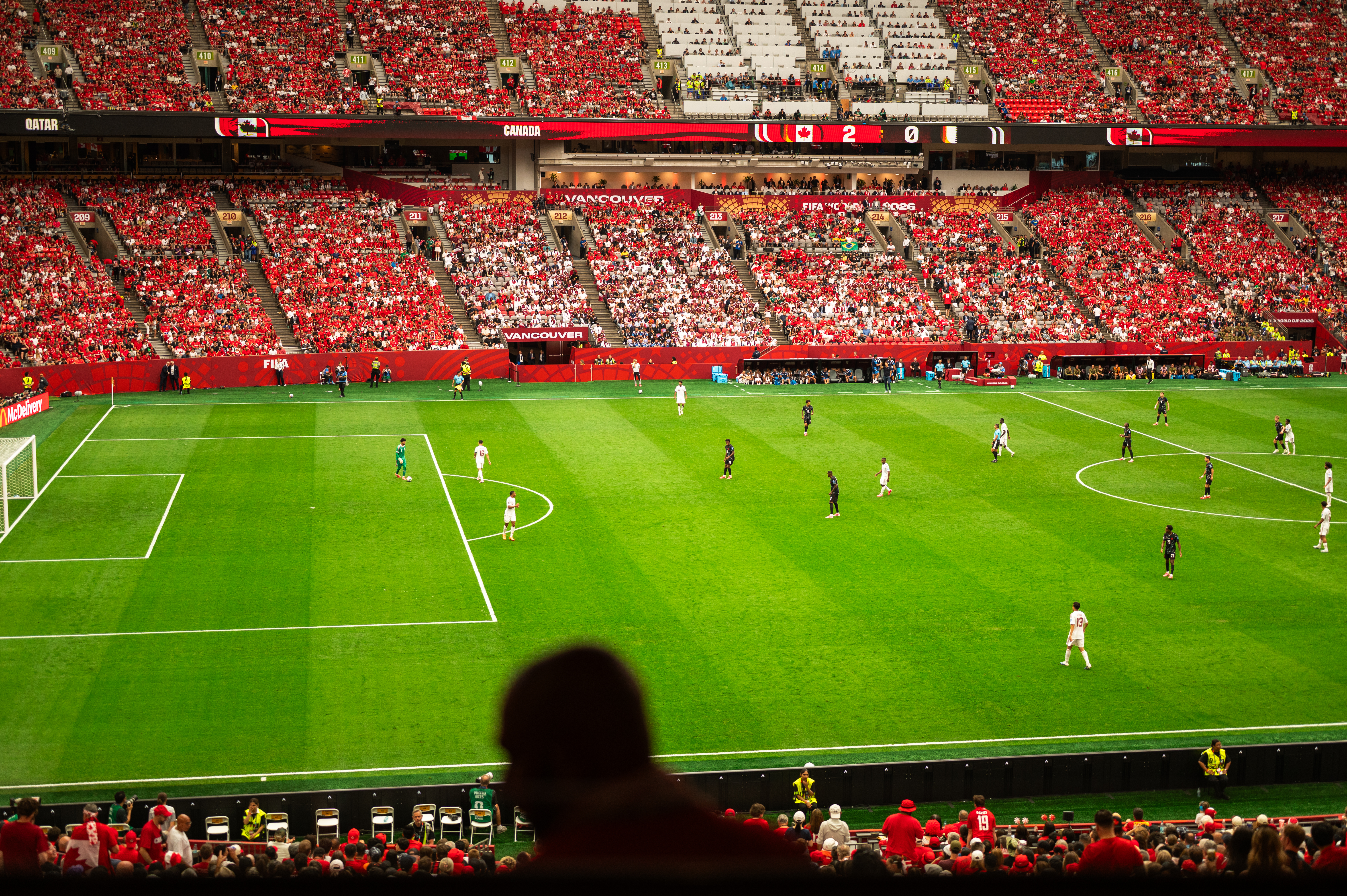 World Cup soccer stadium with packed red stands and players on the green field