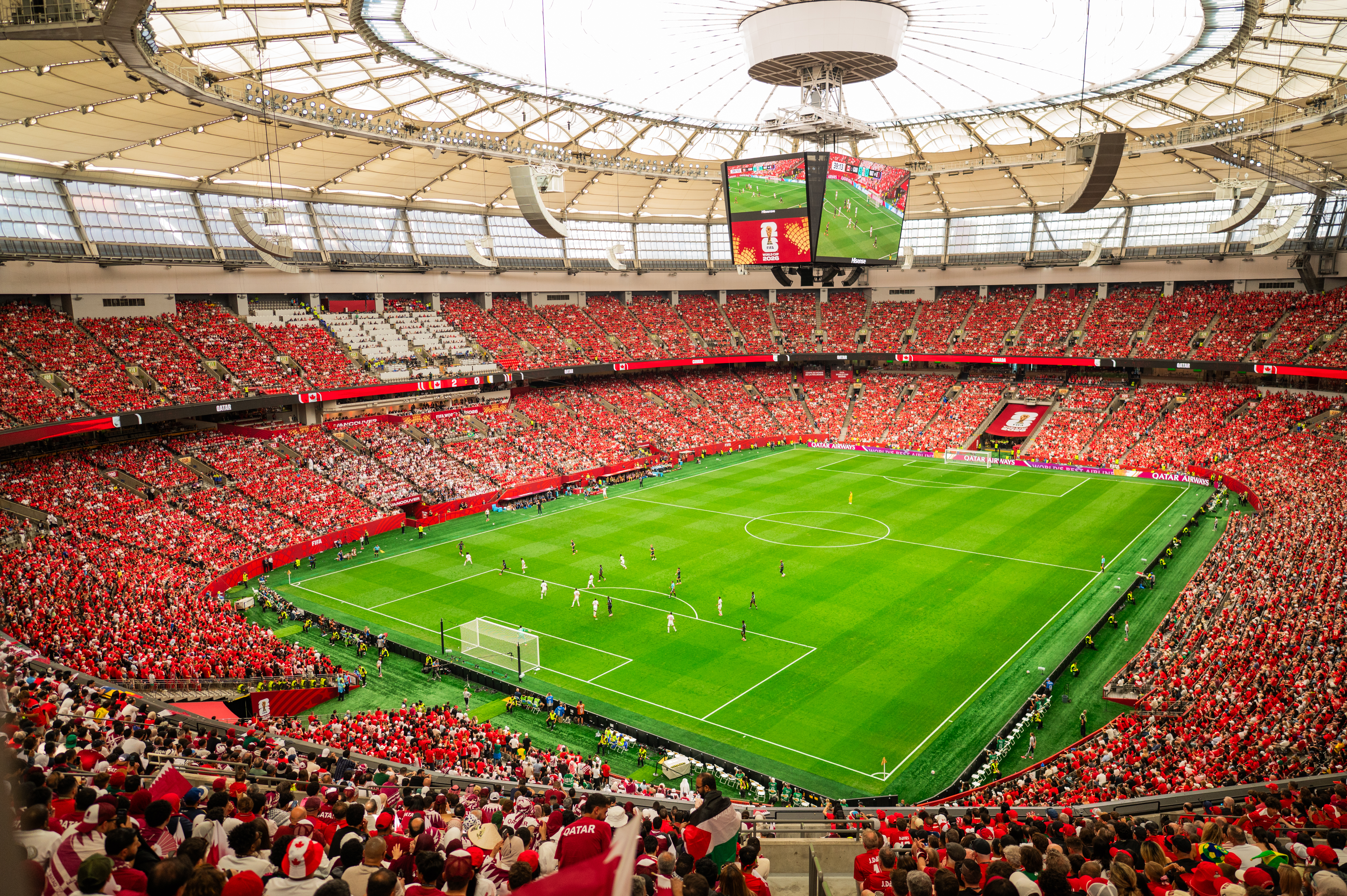 World Cup soccer stadium filled with cheering fans, large video screen, and green field