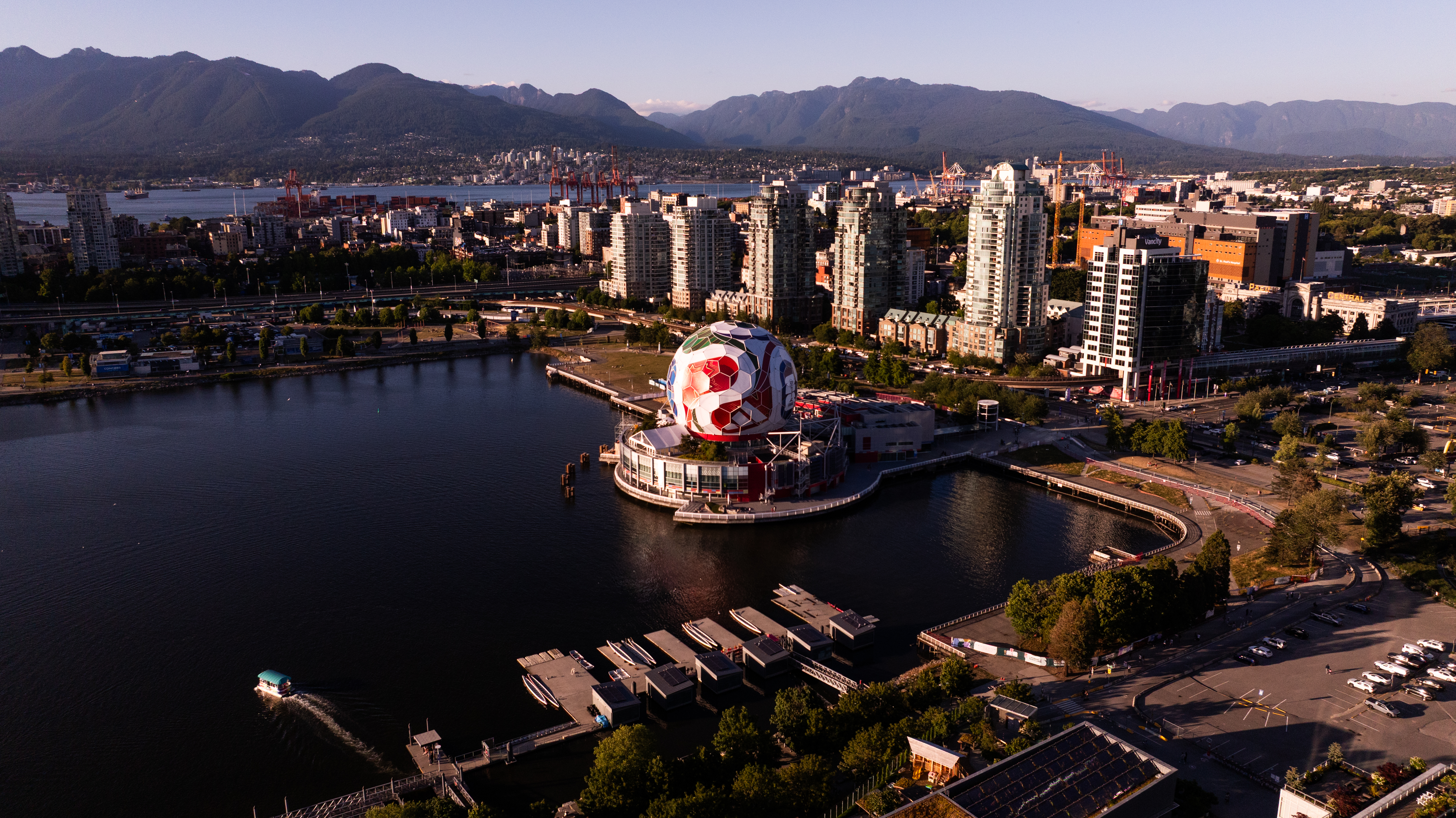 Vancouver cityscape from above, featuring False Creek, mountains, and a large soccer ball structure