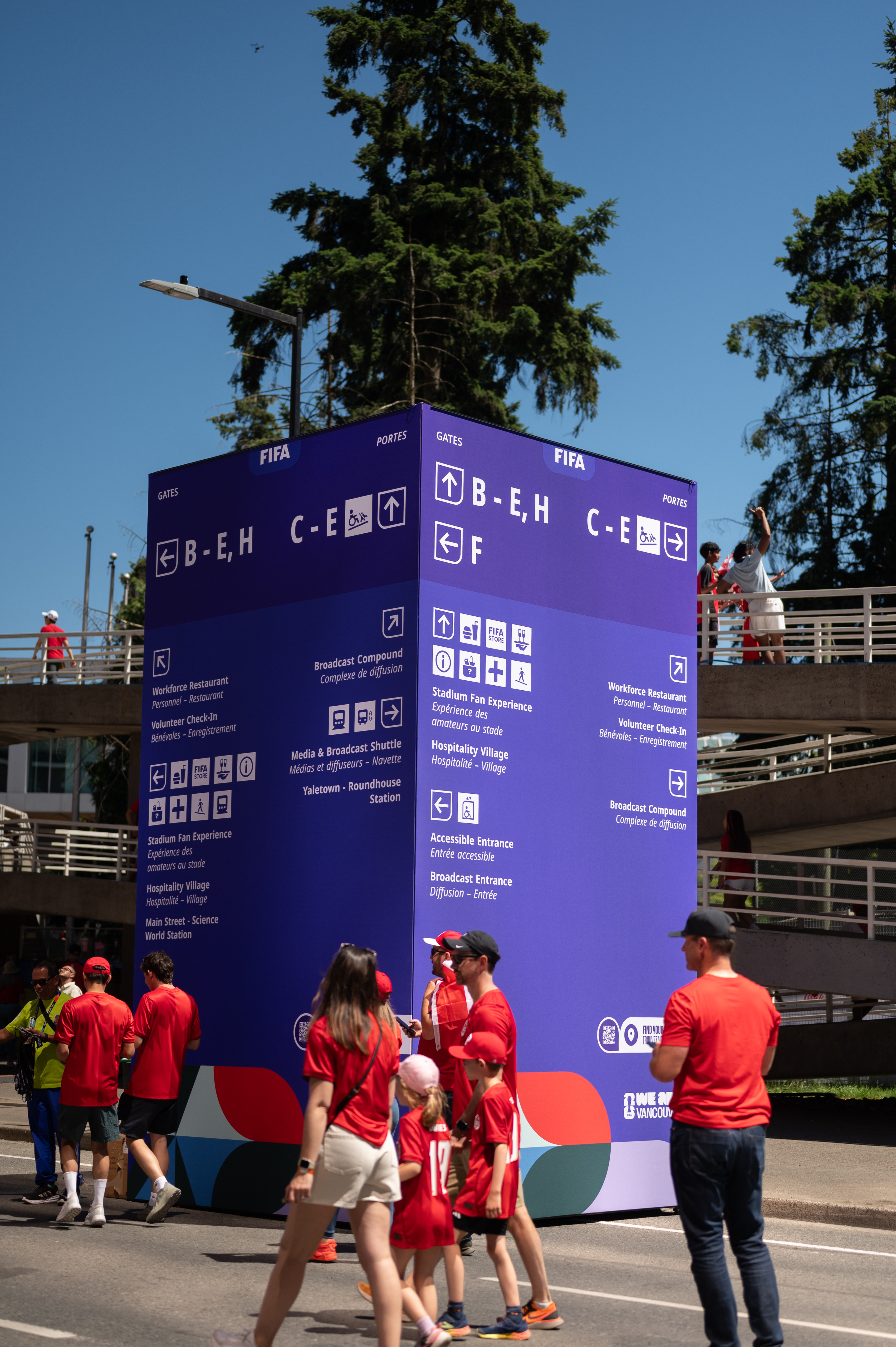 Large purple FIFA directional signs guide people through a city street for a major event