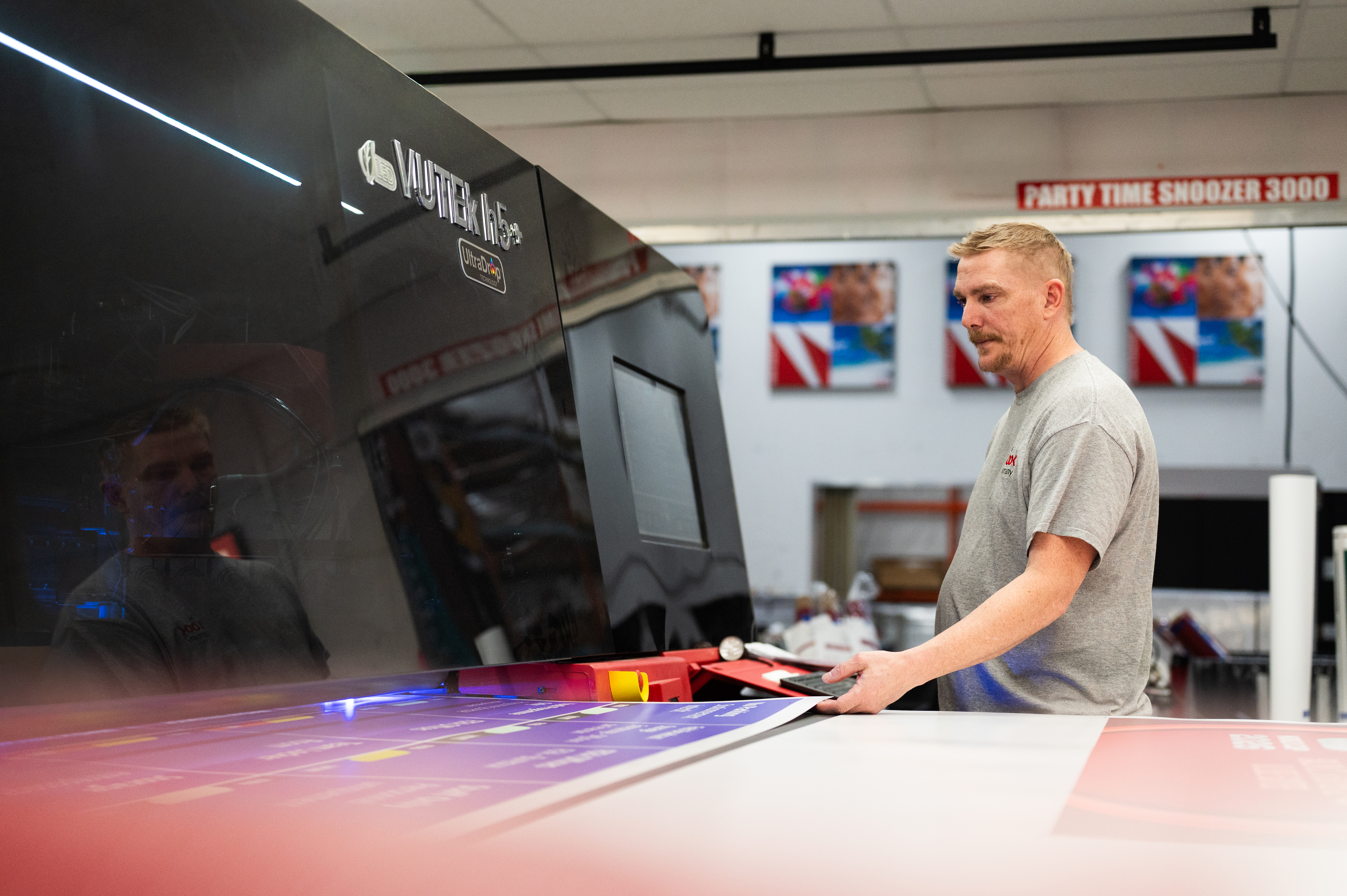 Man operating a large VUTEK h5 printer, producing large format event graphics