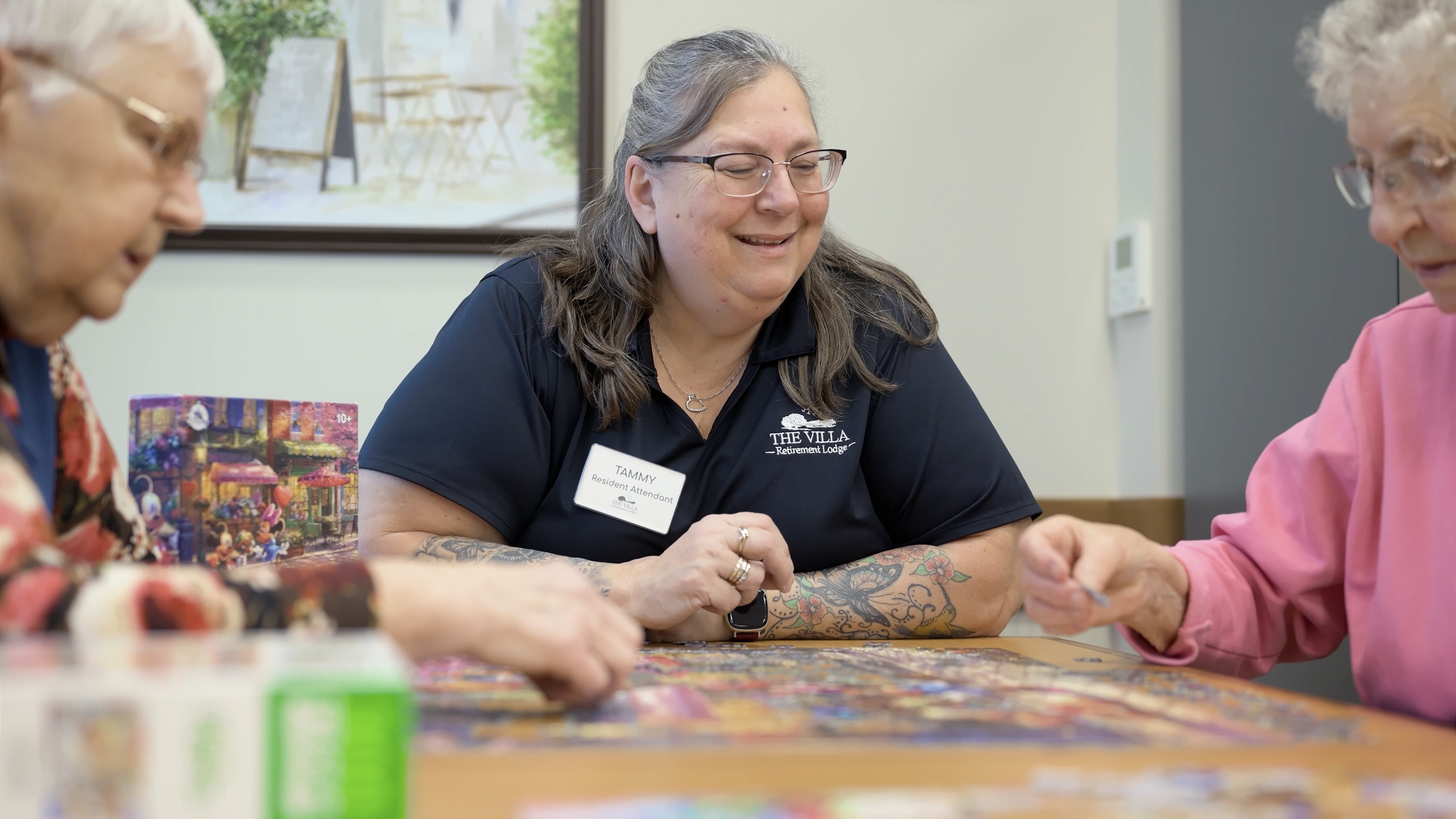 Smiling Jarlette Health Services attendant Tammy doing a puzzle with two residents