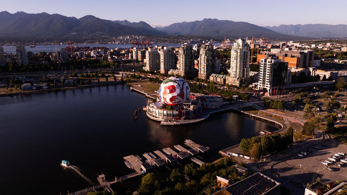 Vancouver cityscape from above, featuring False Creek, mountains, and a large soccer ball structure